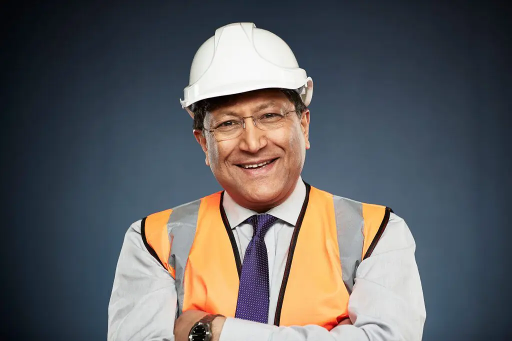 Homme souriant portant un casque de sécurité blanc et un gilet orange, représentant le statut de salarié protégé CSE.