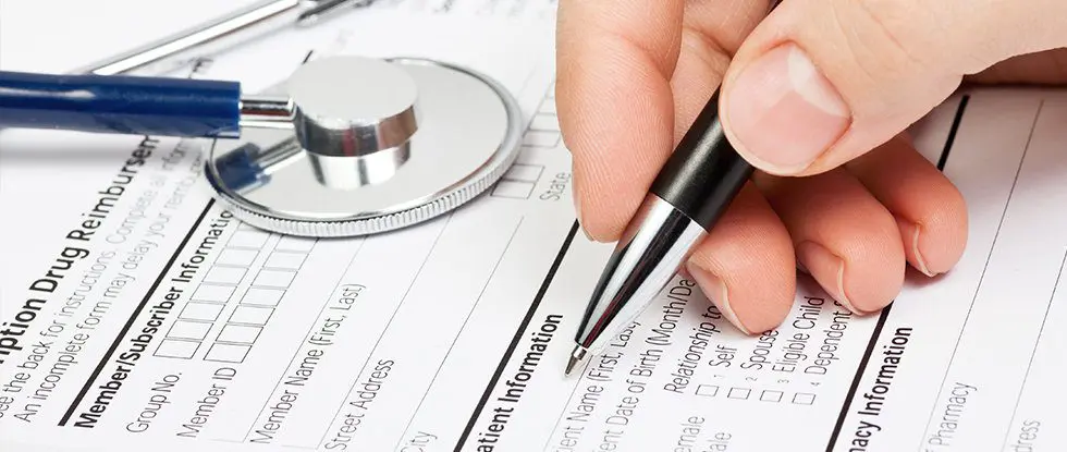 Main d'un médecin remplissant un formulaire de suivi médical avec un stéthoscope