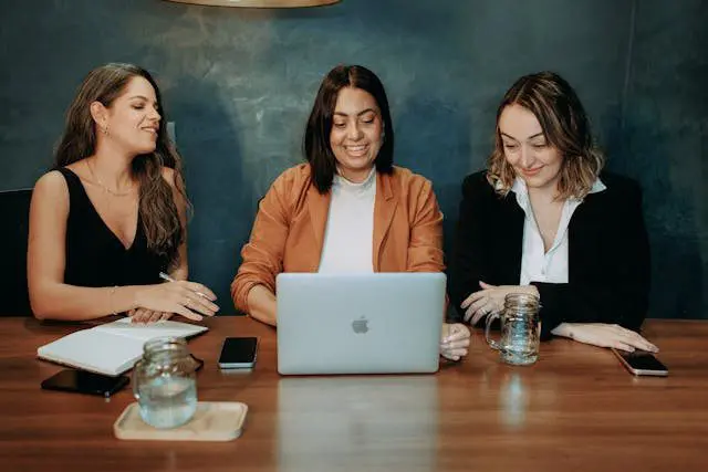 Trois femmes discutent devant un ordinateur portable, possiblement en formation sur le délit d'entrave CSE.
