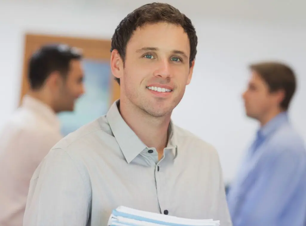 Homme souriant tenant des documents, contexte professionnel