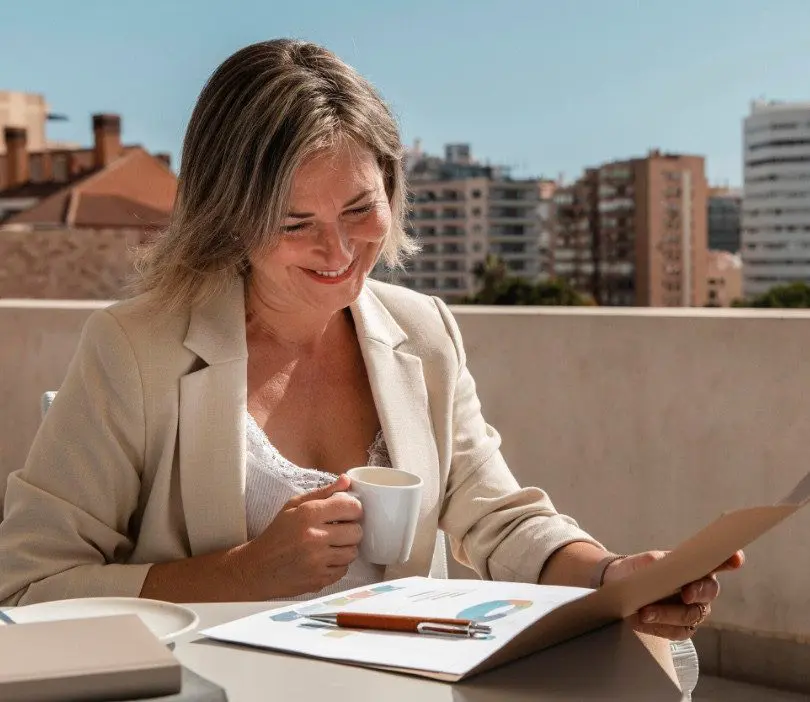 Femme souriante consultant des documents avec une tasse de café, formation CSE Montpellier
