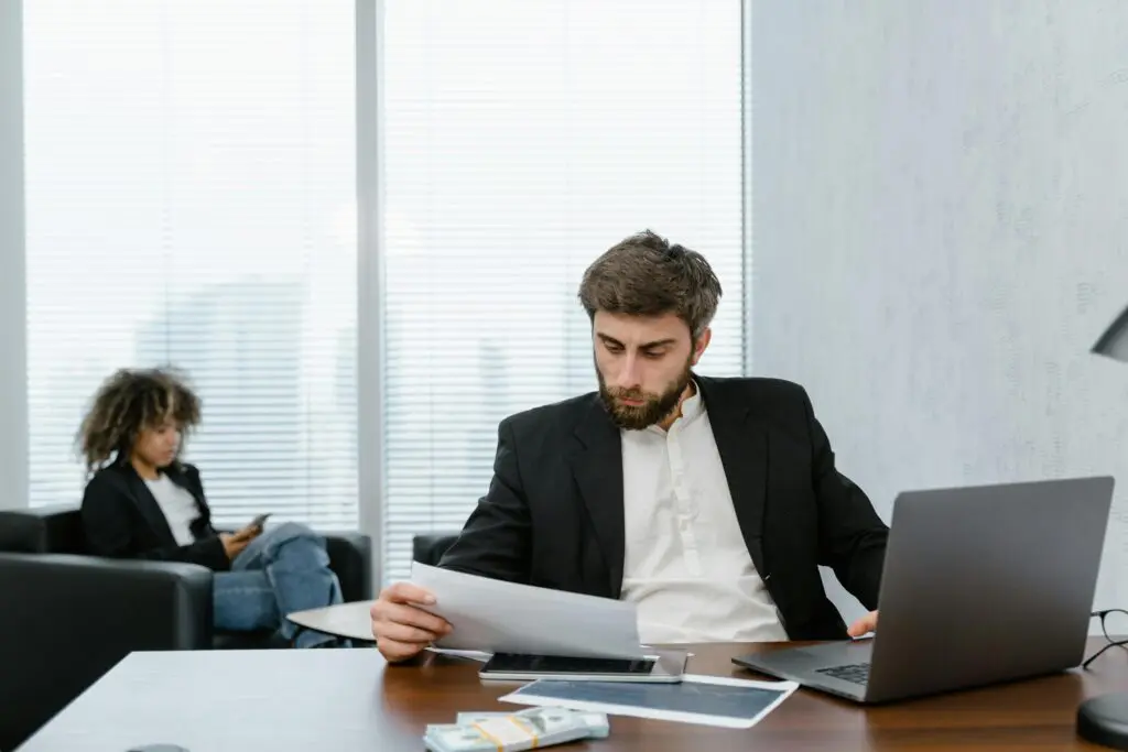 Homme d'affaires lisant des documents près d'un ordinateur portable