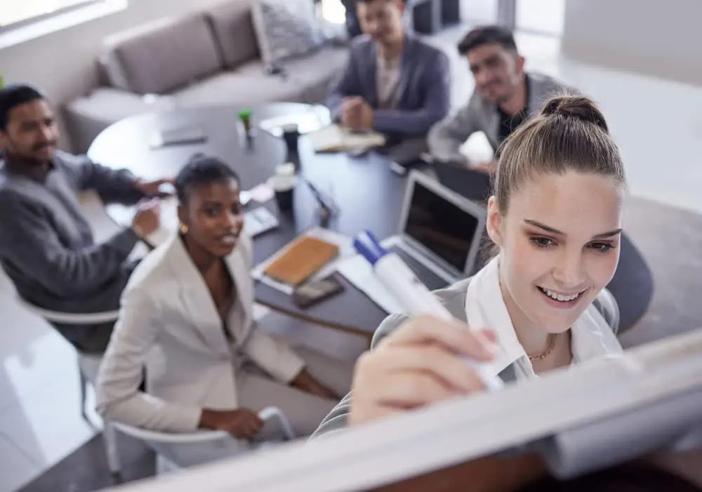 Femmes et hommes en réunion de formation SSCT, un groupe discute devant un tableau blanc.